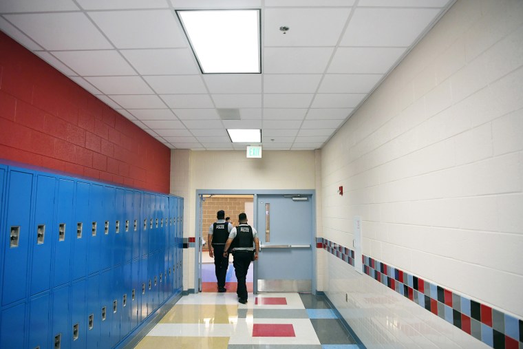 Image: Alexandria Police Department school resource officers walk through a hallway at T.C. Williams High School on June 9, 2021 in Alexandria, Va.