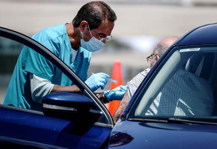 A health care worker administers a vaccination at a drive-thru site in Miami.