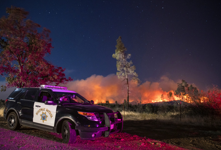 A California Highway Patrol officer watches flames visible from the Zogg Fire near Igo, Calif., on Sept. 28. 2020.