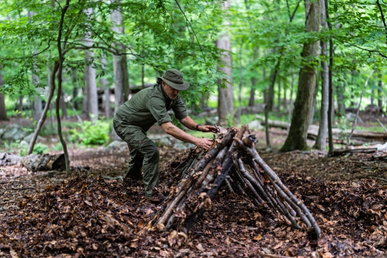 Shane Hobel works on a debris hut shelter at the Mountain Scout Survival School in Hopewell Junction, N.Y., on July 10, 2021.