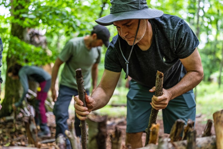 David D'Alessio, from Harlem, New York City, helps to build a debris hut shelter at the Mountain Scout Survival School.