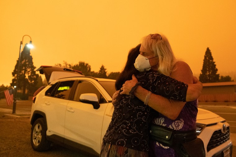 Evacuated residents hug near State Route 89 during the Dixie Fire in Greenville, Calif., on July 24.