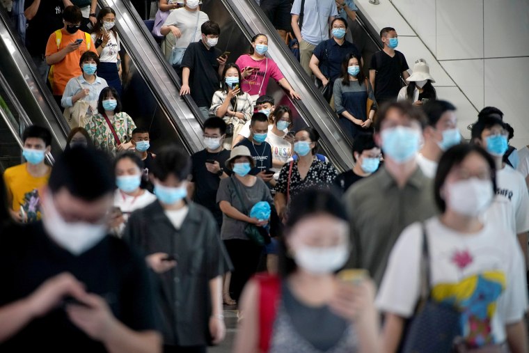 Image: People wearing protective masks ride escalators inside a subway station, following new cases of the coronavirus disease (COVID-19), in Shanghai
