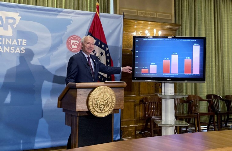 Asa Hutchinson stands next to a chart displaying Covid hospitalization data at the state Capitol in Little Rock, Ark., on July 29, 2021.