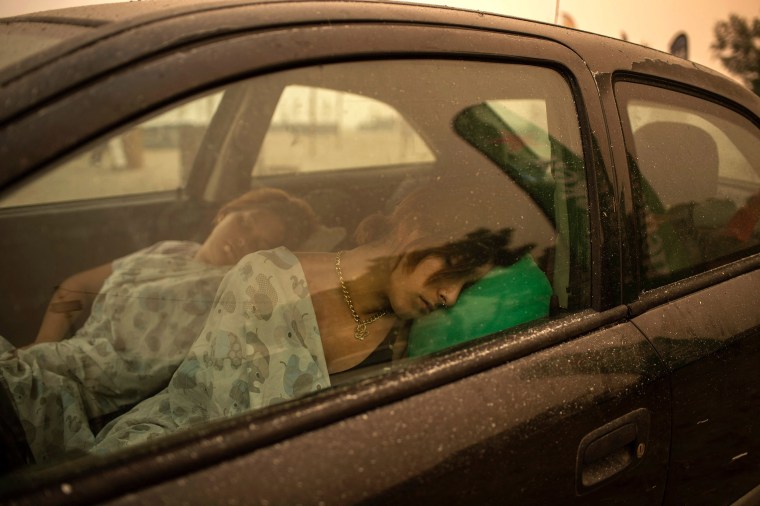 Image: A woman sleeps in her car on the beach as wildfire rages in Pefki village on Evia island, Greece,