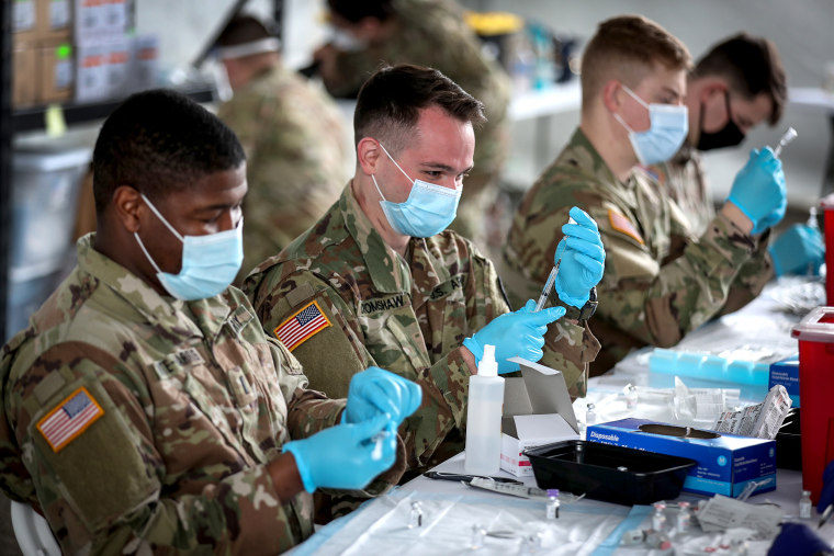 U.S. Army soldiers from the 2nd Armored Brigade Combat Team, 1st Infantry Division, prepare Pfizer Covid-19 vaccines to inoculate people at the Miami Dade College North Campus on March 9, 2021 in North Miami.