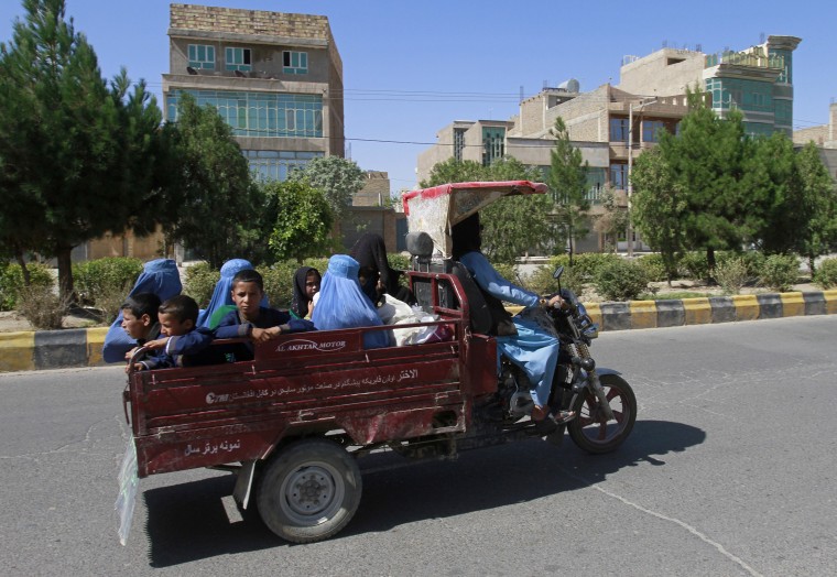 Image: Afghan women and children travel in a motorcycle cart during fighting between Taliban and Afghan security forces in Herat province