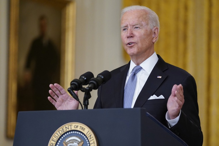 Joe Biden stands in a suit and tie behind an official podium, hands up in a defensive position