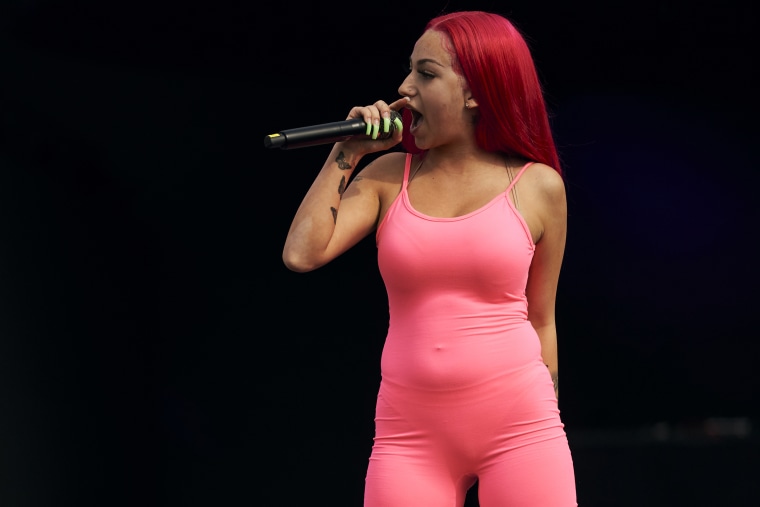 Bregoli in a hot pink unitard with bright pink hair holds a microphone close to her face in front of a black background