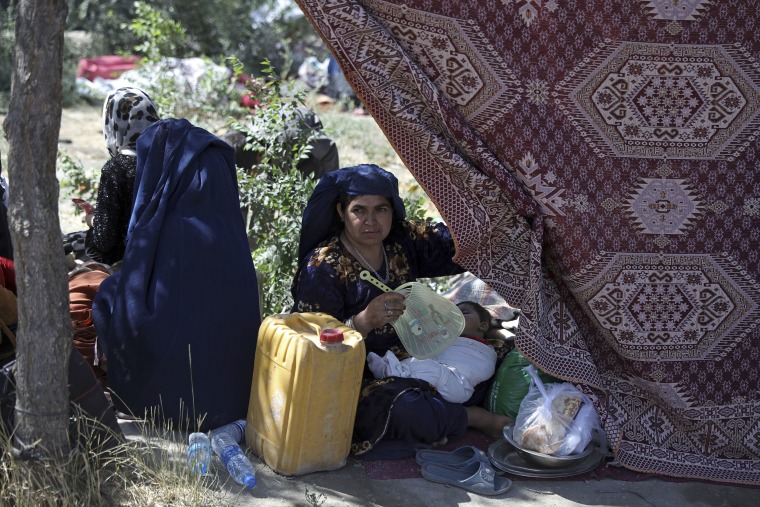 An Afghan woman from a northern province who fled her home due to fighting between the Taliban and Afghan security personnel fans her sleeping child in a public park in Kabul.