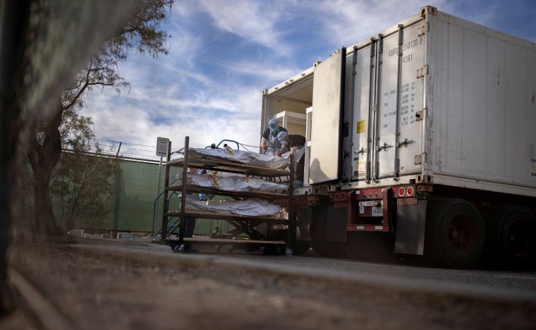 El Paso County Medical Examiner's Office staff help move bodies in bags labeled "Covid" from refrigerated trailers on Nov. 23, 2020.