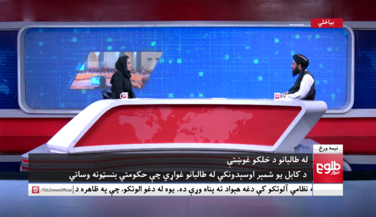 Image: A female news anchor talks to a member of the Taliban on Afghan news channel Tolo News.