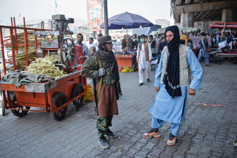 A Taliban fighter stands by a kiosk selling sugarcane juice at a market area in the Kote Sangi area of Kabul on Aug. 17, 2021.