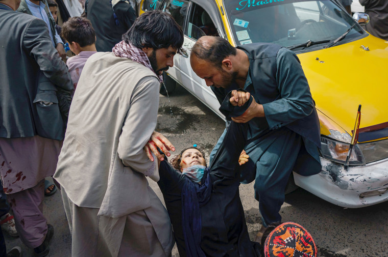 Image: Men try to help a wounded woman and her child after Taliban fighters use gun fire, whips, sticks and sharp objects to maintain crowd control over thousands of Afghans who continue to wait outside Kabul Airport, Afghanistan