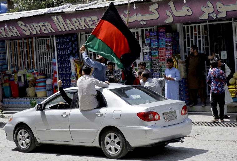 Image: Afghans wave a black, red and green banner in honor of the Afghan flag.