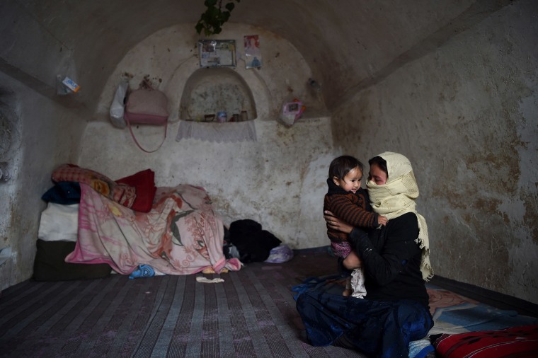 Image: A Hazara woman holds her child inside a cave where they live in the Tak Darakht village on the outskirts of Bamiyan province on March 6.