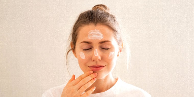 Woman applying face cream in a bathroom