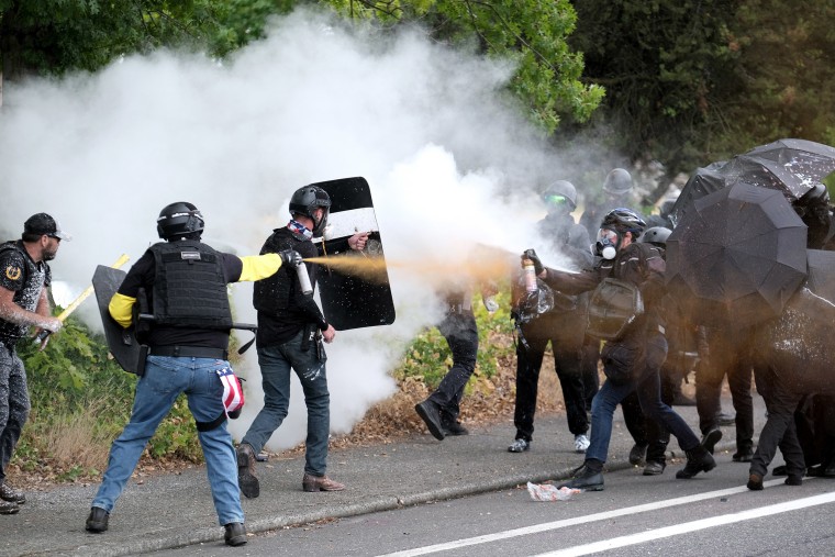 Image: Members of far-right and left-wing groups spray bear mace at each other during clashes between the politically opposed sides on Sunday in Portland, Ore.