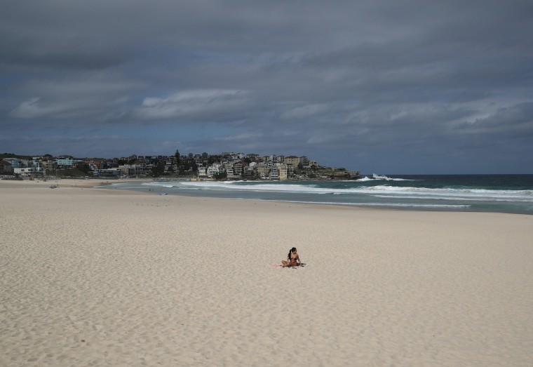 Image: A single sunbather remains following the closure of Bondi Beach in Sydney, Australia