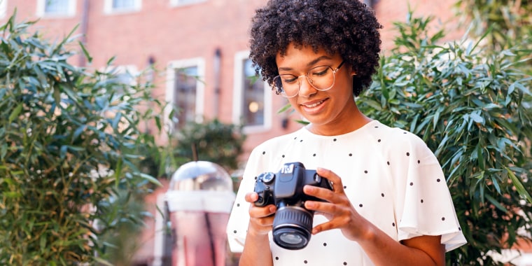 Woman sitting outside looking at a DSLR Camera