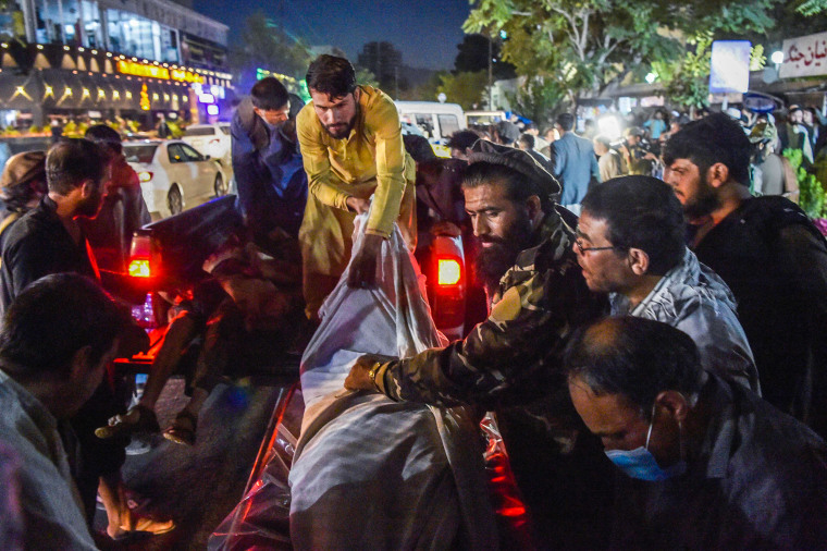 Image: Volunteers and medical staff unload bodies from a pickup truck outside a hospital after two powerful explosions, which killed at least six people, outside the airport in Kabul on Aug. 26, 2021.