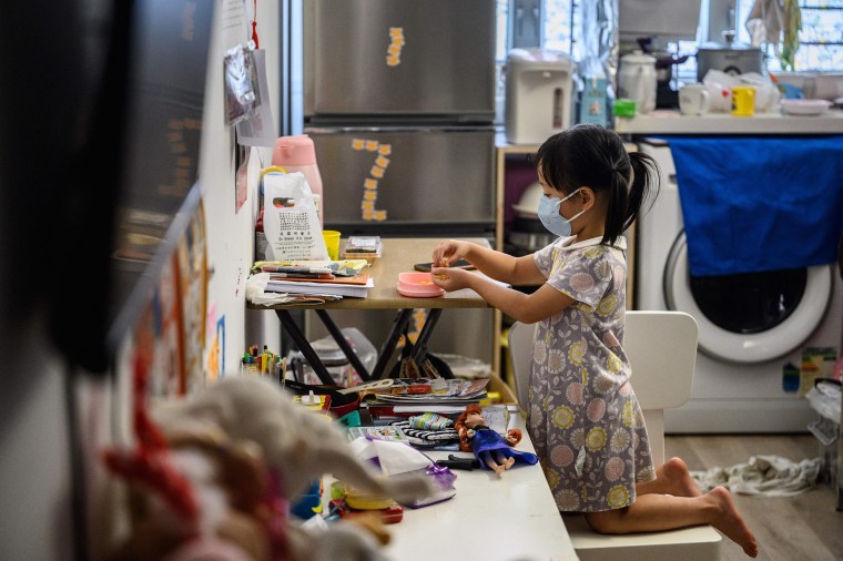 Image: A child eats a snack in her temporary 290 square-foot studio flat in Hong Kong.