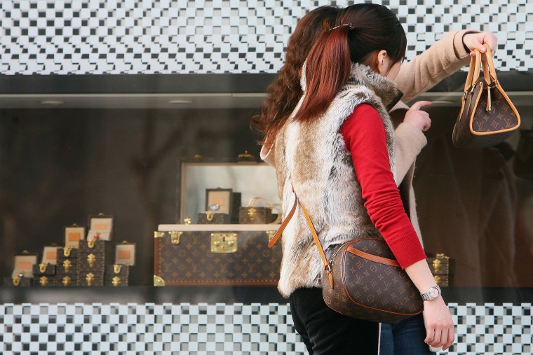 Image: Chinese Women view the bags they bought at a Louis Vuitton flagship store Shanghai, China.