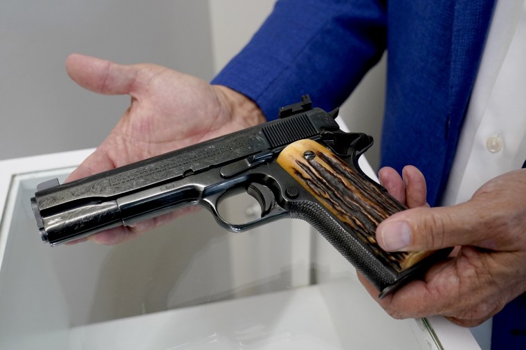 Image: Brian Witherell displays a Colt .45-caliber pistol that once belonged to mob boss Al Capone, at Witherell's Auction House in Sacramento, Calif., on Aug. 25, 2021.