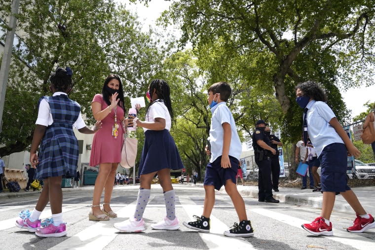 Image: A teacher greets students outside of iPrep Academy on the first day of school on Aug. 23, 2021, in Miami.