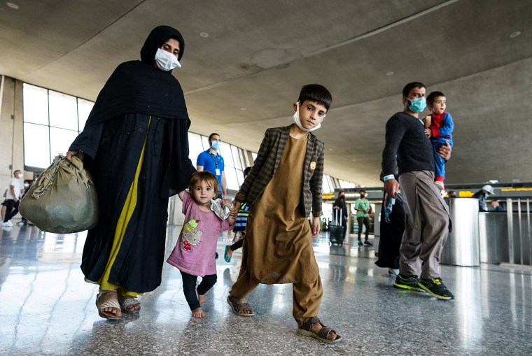 Image: Afghan refugees walk to a bus taking them to a processing center upon arrival at Dulles International Airport in Dulles, Va., on Aug. 27, 2021.
