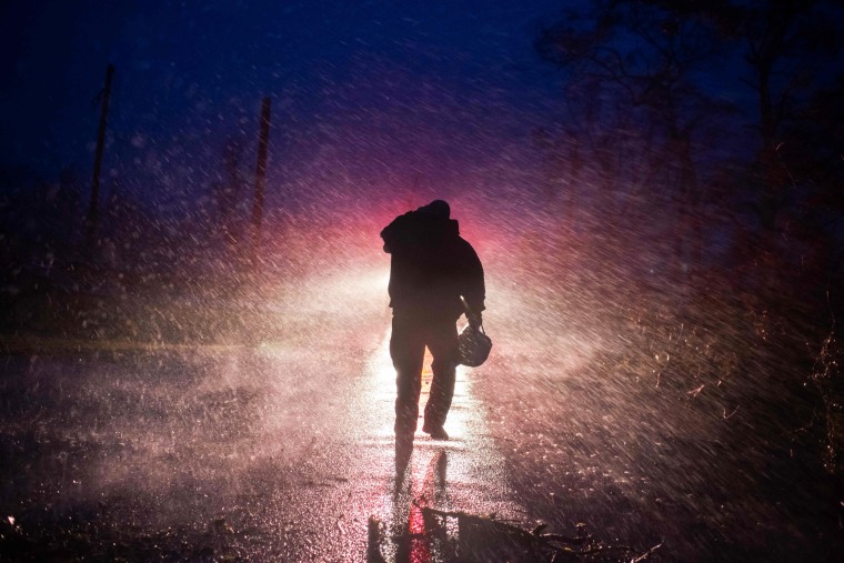 Montegut fire chief Toby Henry walks back to his fire truck in the rain as firefighters cut through trees on the road in Bourg, La., as Hurricane Ida passes on Sunday.