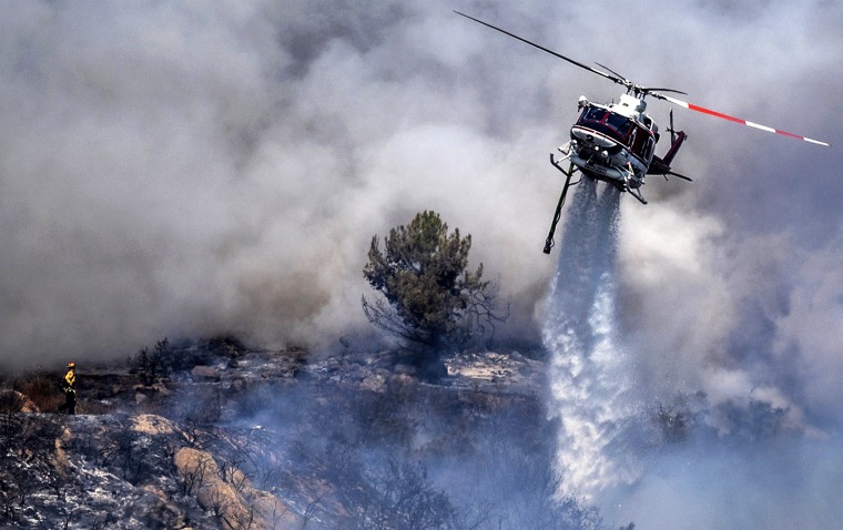A helicopter makes an aerial drop at the the Chaparral Fire in Murrieta, Calif., on Aug. 29, 2021.