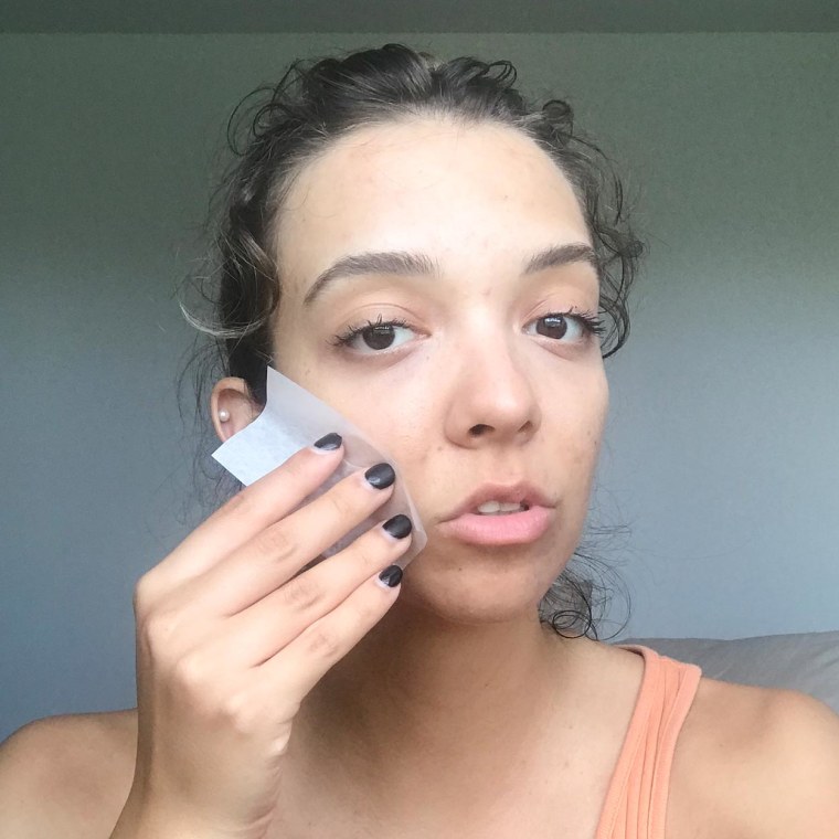 Writer Cailey Rizzo blotting her face with an oil blotter