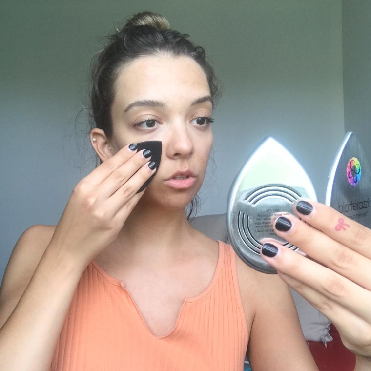 Writer Cailey Rizzo blotting her face with an oil blotter