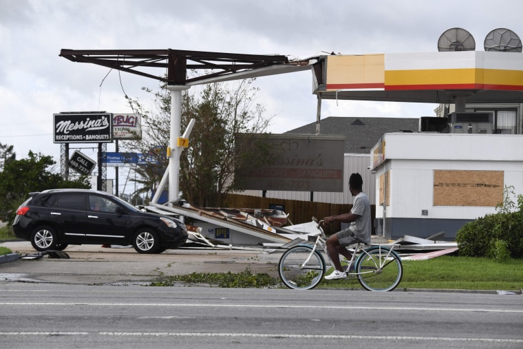 A person on a bicycle passes a damaged Shell station in Kenner, La., on Aug. 30, 2021, after Hurricane Ida made landfall.