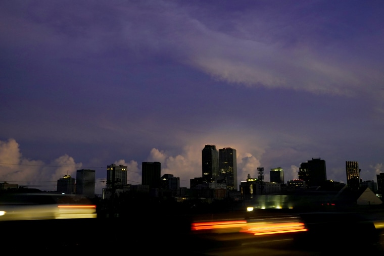 Cars pass a mostly dark downtown along Interstate 10 in New Orleans late Monday.