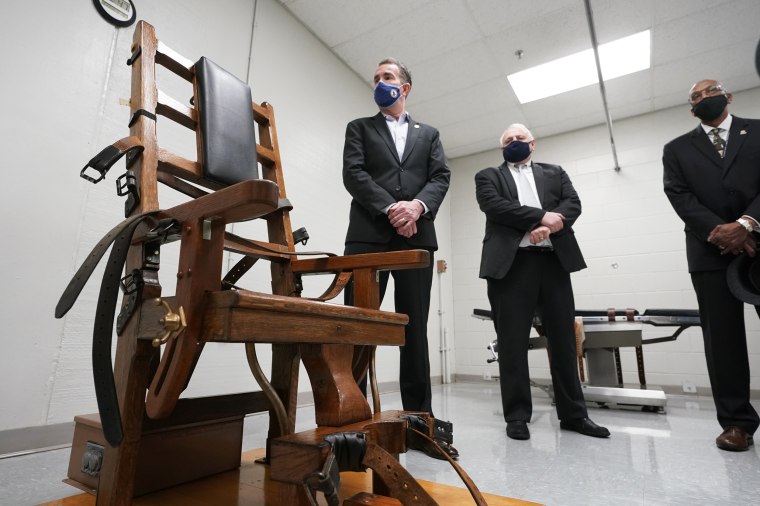 Virginia Gov. Ralph Northam, left, looks over the electric chair in the death chamber at Greensville Correctional Center prior to signing a bill abolishing the penalty in Jarratt, Va., on March 24, 2021.
