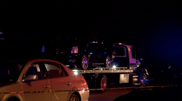 A black SUV sits on a tow truck at nighttime