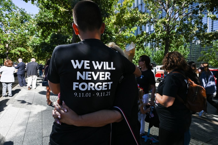 Manuel DaMota wears a shirt that reads "We Will Never Forget 9.11.01-9.11.21" as he embraces his mother Barbara.