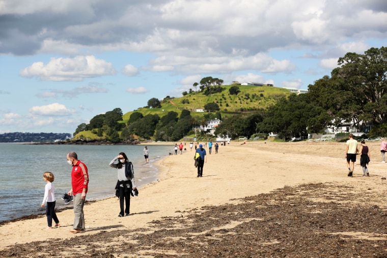 People walk on the beach in Auckland, New Zealand, on Sept. 2, 2021.