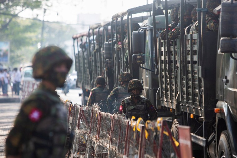 Image: FILE PHOTO: Soldiers stand next to military vehicles as people gather to protest against the military coup, in Yangon