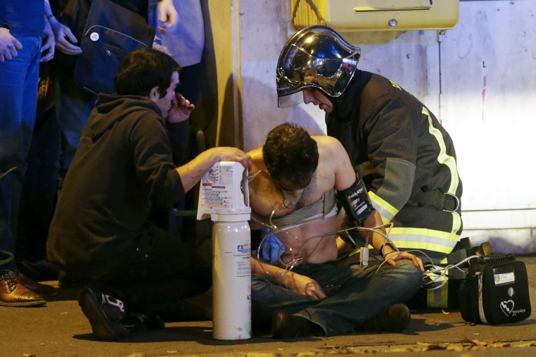 FILE PHOTO: French fire brigade members aid an injured individual near the Bataclan concert hall following fatal shootings in Paris, France