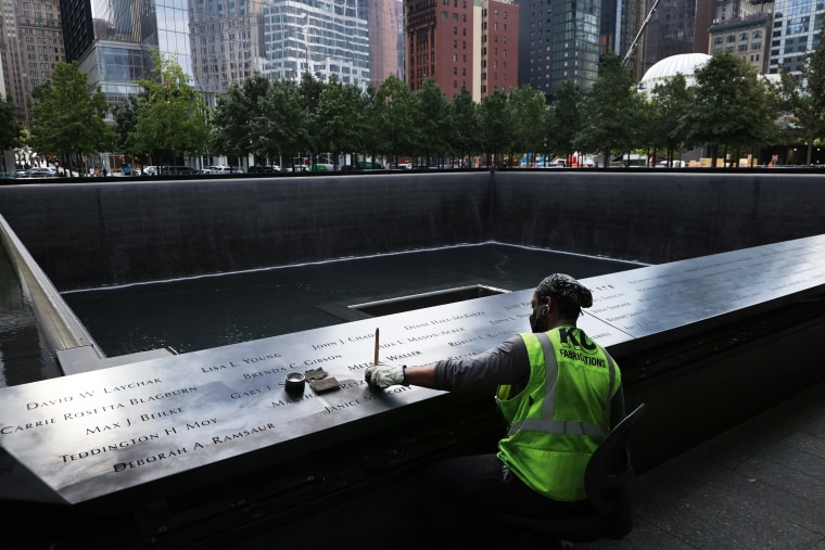 A worker polishes the bronze parapets surrounding the twin memorial pools where the names of the men, women, and children killed in the 9/11 attacks are inscribed in New York on Sept. 8, 2021.