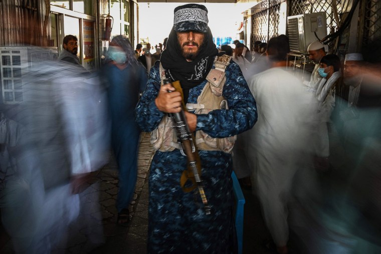 A Taliban fighter stands guard as people move past him at a market in Kabul on Sept. 5, 2021.