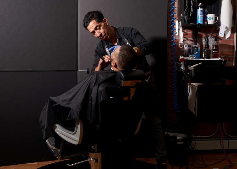 Image: Rafael Almonte with a customer at La Fama, his barbershop, in Nashua, N.H, on Sept. 11.
