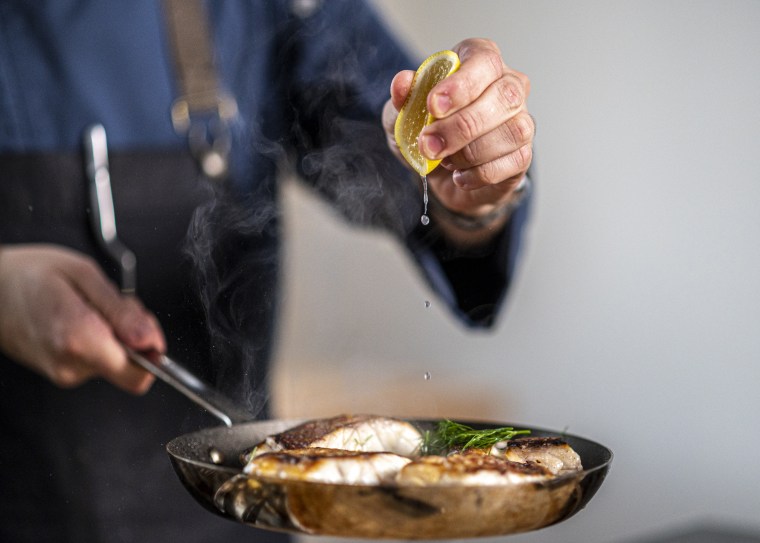 Image: Chef and entrepreneur Omar Pereney squeezes lemon onto a fish in a pan at his test kitchen in Houston on Sept. 13.