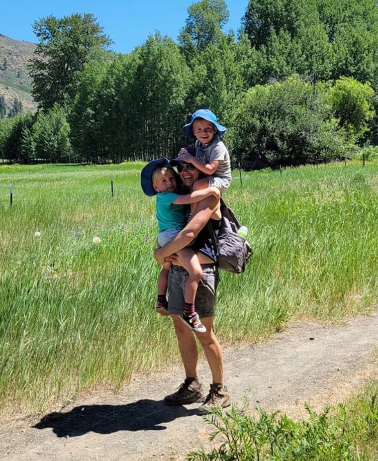 Woman outdoors carrying two children