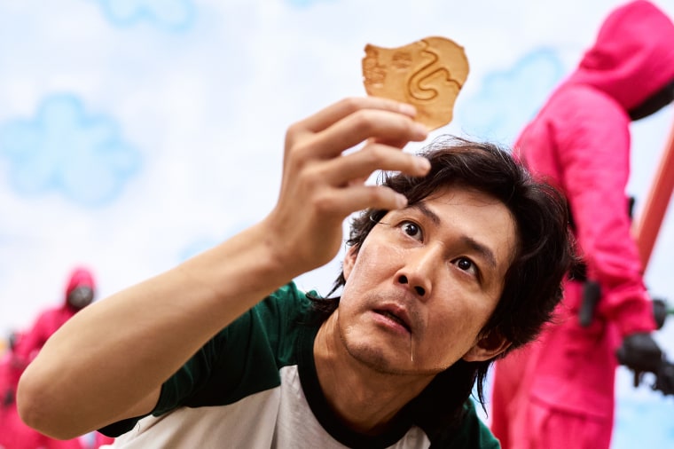 In one scene of "Squid Game," competitors have to separate a shape from a fragile candy known as a dalgona cookie. Here, main character Seong Gi-hun (Lee Jung-jae) struggles to separate a complex umbrella shape. 