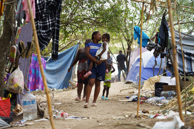 Haitian migrants walk in a makeshift encampment where more than 12,000 people hoping to enter the United States await under the international bridge in Del Rio, Texas, on Sept. 21, 2021.