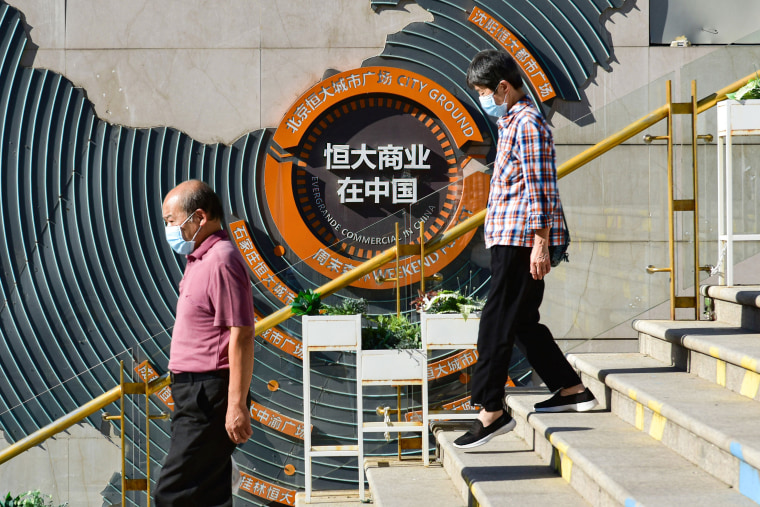 IMAGE: People pass in front of Evergrande group's blueprint for